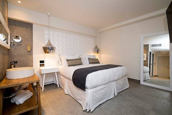 Schlafzimmer im Insula Alba Resort & Spa mit einem großen Bett, grauen Böden und weißen Wänden.