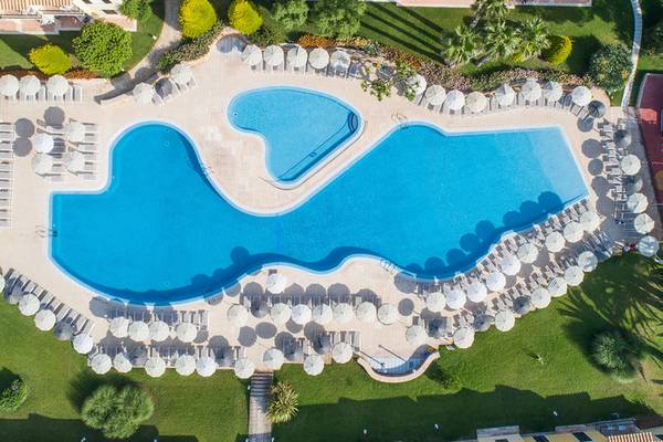 Gruppenhotel mit Swimmingpool und Liegestühlen auf der Terrasse.