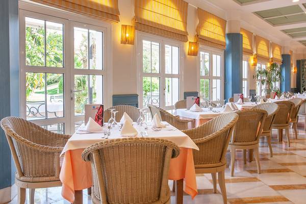 Restaurantbereich im Grupotel Playa Club mit Tisch und Stühlen, Fenstern und gelben Vorhängen