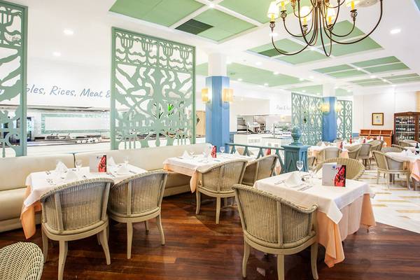 Innenansicht des Restaurants im Grupotel Playa Club mit gemusterten Wänden und einer großen Kronleuchter.