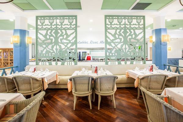 Innenansicht des Restaurants im Grupotel Playa Club mit grünen Wänden und blauen Säulen.