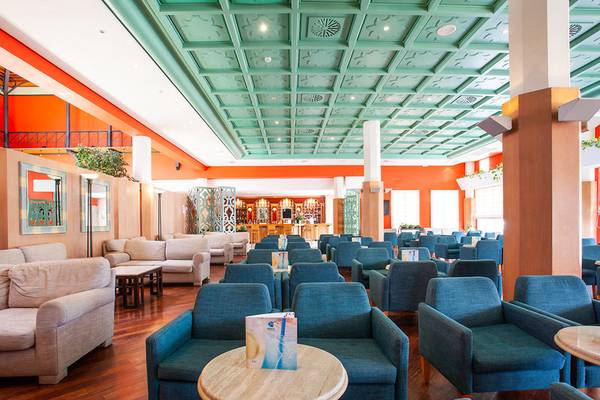 Lobby des Grupotel Playa Club Hotels mit blauen Sesseln, Holzboden und türkisfarbener Decke.