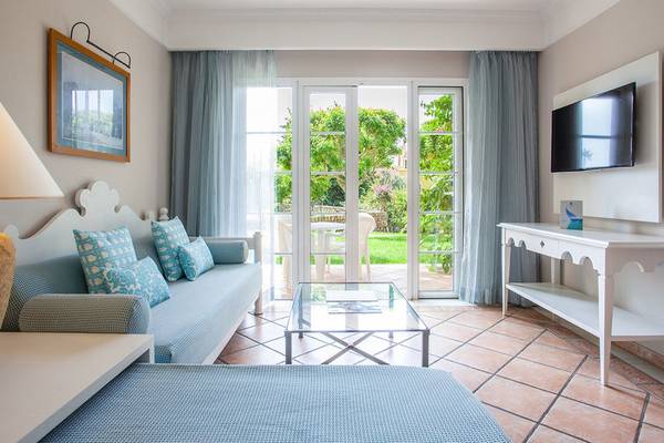 Wohnzimmer im Hotel Grupotel Playa Club mit blauer Couch, Glastisch und Fernseher