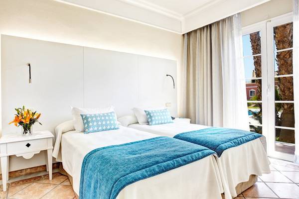 Doppelzimmer im Grupotel Playa Club mit zwei Betten, blauen Decken, weißen Kissen und einem weißen Nachttisch.