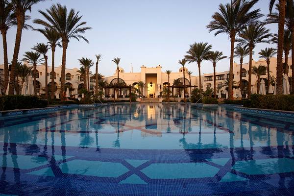 Außenpool des Pickalbatros The Palace Port Ghalib Hotels mit Palmen und Gebäude im Hintergrund