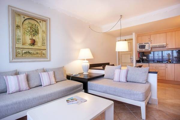 Wohnbereich des Grupotel Macarella Suites & Spa mit zwei Sofas, einem Tisch und einer Küche im Hintergrund.