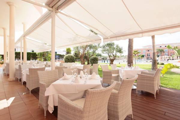 Restaurantterrasse des Grupotel Macarella Suites & Spa mit gedeckten Tischen und Stühlen.