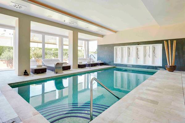 Innenpool des Grupotel Macarella Suites & Spa mit Liegestühlen und Handläufen