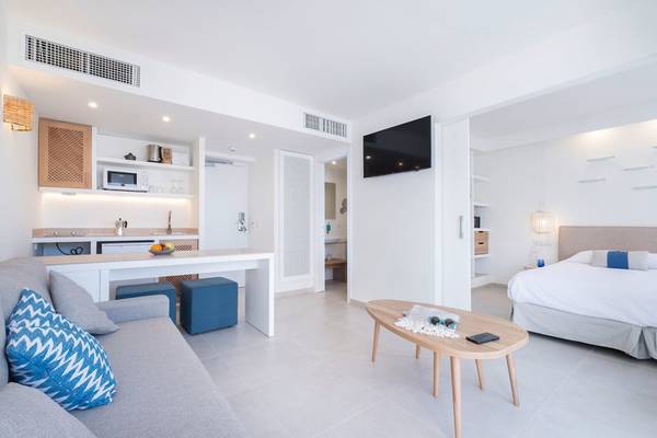 Innenansicht des Carema Beach Menorca Hotels mit Wohnzimmer, Couch, Tisch und Fernseher