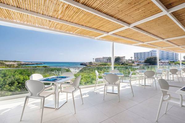 Terrasse des Carema Beach Menorca Hotels mit Blick auf das Meer und weiße Möbel