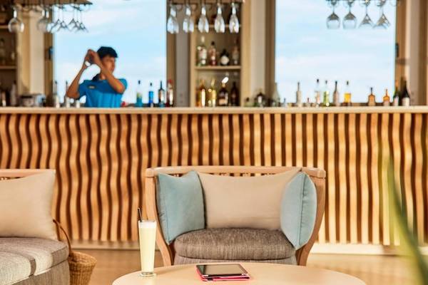 Innenansicht der Bar im Victoria Menorca Hotel mit Barkeeper, Getränken und Möbeln.