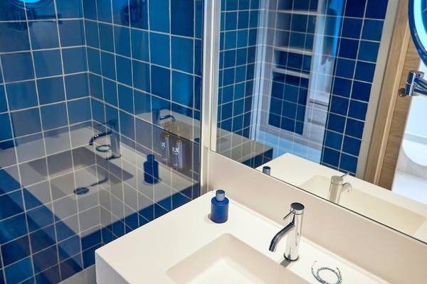 Badezimmer mit blauen Fliesen und einem Spiegel im Hotel Victoria Menorca.