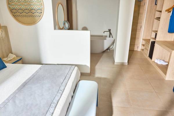 Innenansicht des Schlafzimmers im Victoria Menorca Hotel mit Bett, Badewanne und Kleiderschrank.