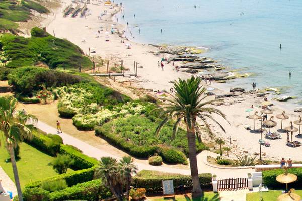 Aussicht auf den Strand vor dem Hotel Seth 55 Santo Tomás mit vielen Gästen und Palmen.