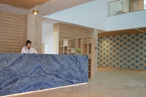 Rezeption des Seth 55 Santo Tomás Hotels mit marmorner Theke und blauem Hintergrund