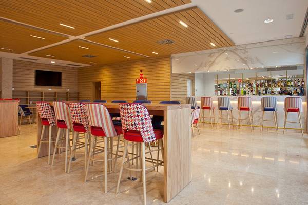 Innenbereich der Bar im Seth 55 Santo Tomás Hotel mit Holztischen, farbenfrohen Stühlen und einer Bar im Hintergrund.