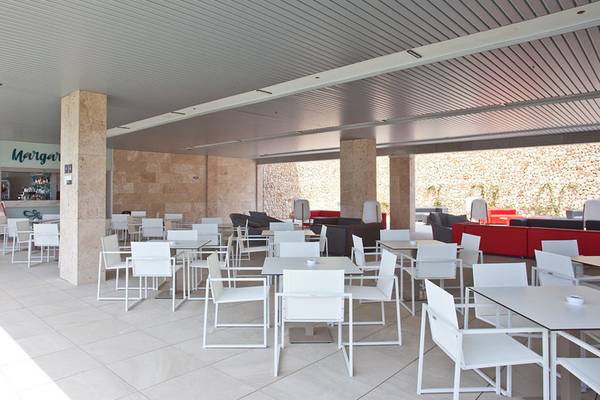 Innenlounge des Seth 55 Santo Tomás Hotels mit weißen Tischen und Stühlen und einem roten Sofa.
