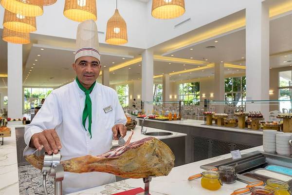 Koch im Senator Puerto Plata Spa Resort Restaurant schneidet ein großes Stück Fleisch.