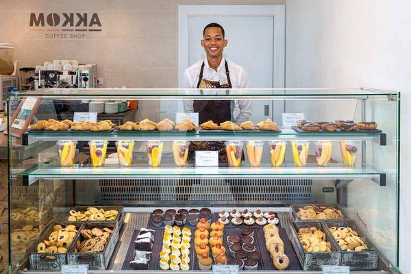 Ein Mitarbeiter des Moxa Coffee Shop steht vor einer Vitrine voller Backwaren.