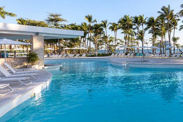 Außenpoolbereich des Senator Puerto Plata Spa Resorts mit weißen Sonnenliegen und Palmen