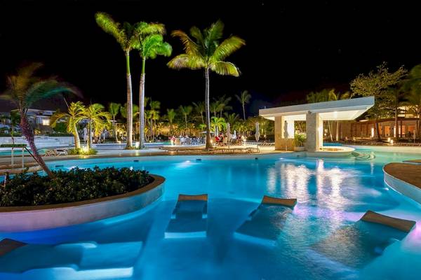 Der Poolbereich des Senator Puerto Plata Spa Resorts bei Nacht mit Palmen und Beleuchtung.