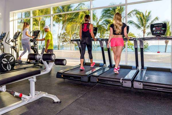 Fitnessstudio im Senator Puerto Plata Spa Resort Hotel mit mehreren Personen auf Laufband und Blick aufs Meer