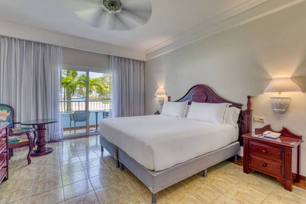 Hotelzimmer im Senator Puerto Plata Spa Resort mit Balkon, Bett, Tisch und Nachttisch.