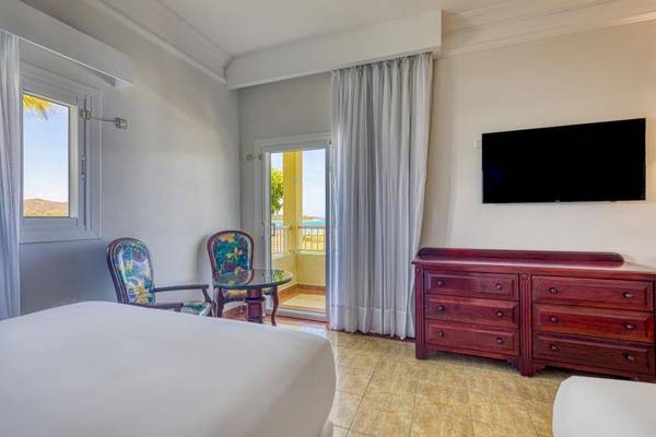 Hotelzimmer im Senator Puerto Plata Spa Resort mit einem Bett, einem Tisch, Stühlen und einem Fernseher.