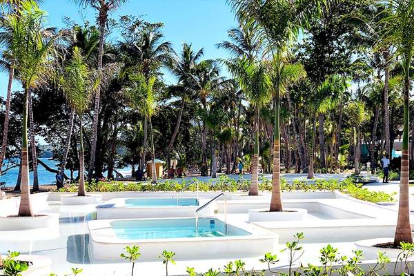 Poolbereich im Senator Puerto Plata Spa Resort mit Palmen und Blick auf das Meer.
