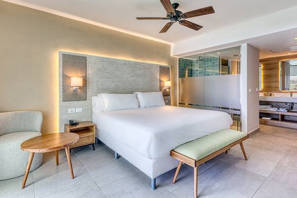 Hotelzimmer im Senator Puerto Plata Spa Resort mit Bett, Nachttisch und Wohnzimmerecke.