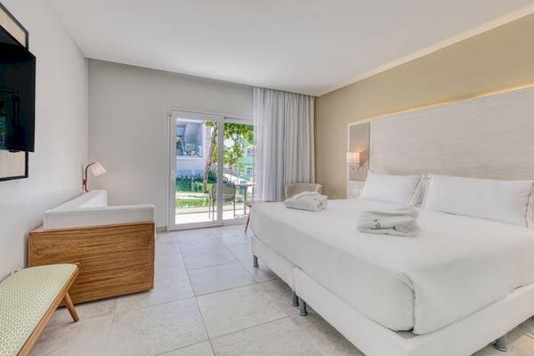 Weißes Hotelzimmer im Senator Puerto Plata Spa Resort mit Doppelbett, Tageslicht und Gartenblick.