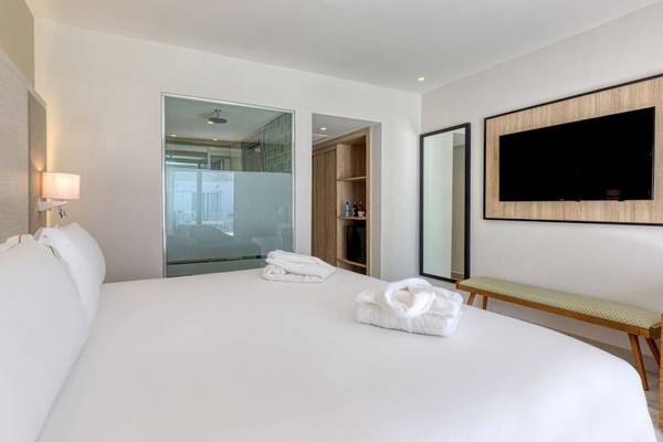 Schlafzimmer im Senator Puerto Plata Spa Resort mit weißem Bett, frischen Handtüchern und moderner Einrichtung.
