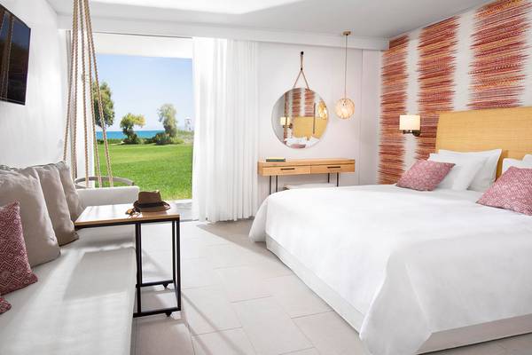 Schlafzimmer im Agapi Beach Resort mit Blick auf das Meer und einen Rasen