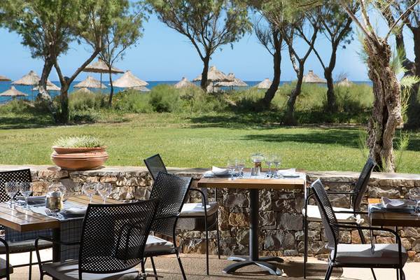 Terrasse des Agapi Beach Resorts mit Blick auf das Meer und Palmen am Strand.