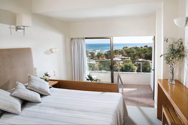Ein Zimmer im Agapi Beach Resort mit Blick auf das Meer und einen Balkon.
