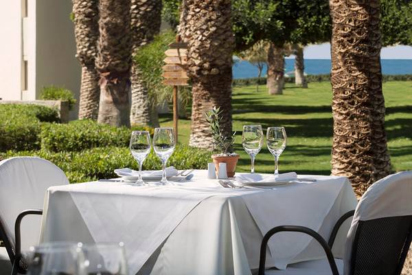 Agapi Beach Resort Außentisch mit Meerblick, Palmen und weißem Tisch