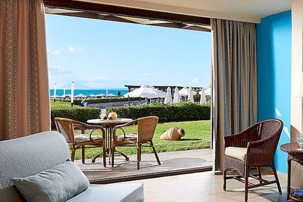 Ein modernes Hotelzimmer mit Blick auf das Meer, dekoriert mit blauen Wänden und einem kleinen Tisch mit einer Lampe.