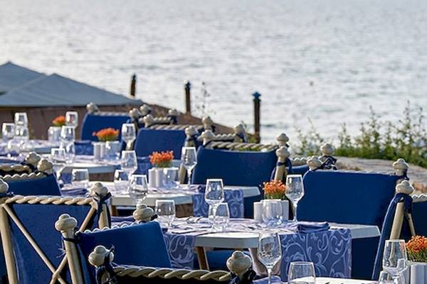 Blick auf das Restaurant des Aldemar Olympian Village mit Tischen und Stühlen am Meer.