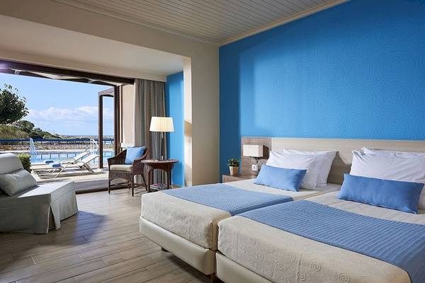 Doppelbett-Zimmer mit blauer Wand, Terrassen-Ausblick und Swimmingpool.