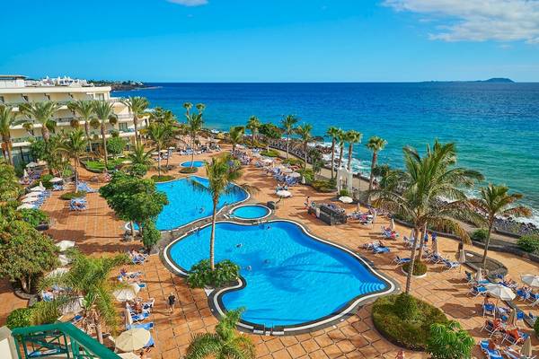 Luftaufnahme des Hipotels Natura Palace Resorts mit zwei Swimmingpools und einer Küste im Hintergrund.