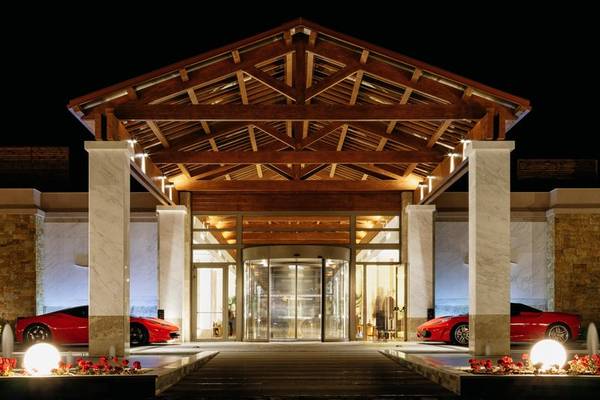Der beleuchtete Eingang des Miraggio Thermal Spa Resorts mit drei roten Sportwagen.