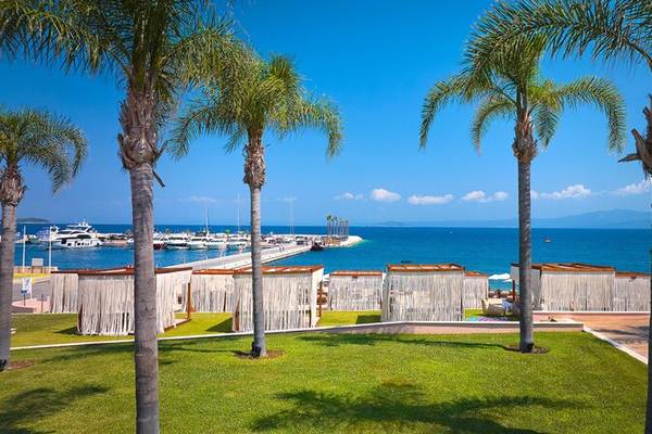 Außenansicht des Miraggio Thermal Spa Resorts mit Blick auf den Hafen, blauem Meer und weißen Segelbooten.