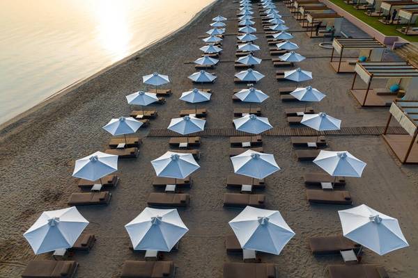 Luftaufnahme von weißen Sonnenschirmen und Liegen am Strand des Miraggio Thermal Spa Resorts