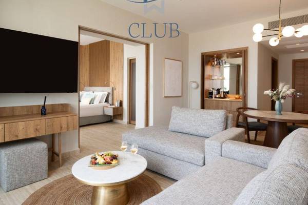 Innenansicht der Club Suite im Miraggio Thermal Spa Resort mit Wohnzimmer, Fernseher, Tisch und Esstisch.