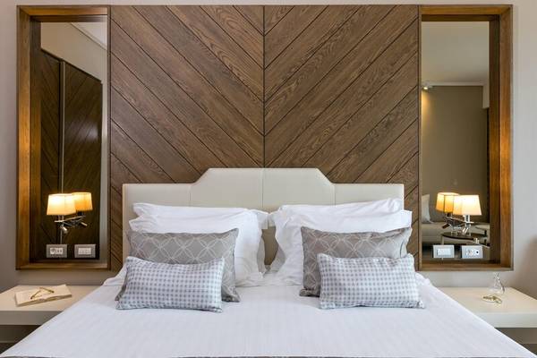 Schlafzimmer im Miraggio Thermal Spa Resort mit Bett, Kissen, Lampen und Holzwand.