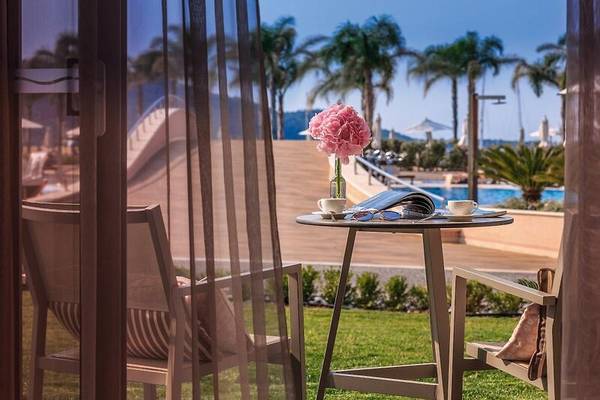 Aussicht aus dem Miraggio Thermal Spa Resort auf einen Pool mit einem Tisch, auf dem eine Blume steht