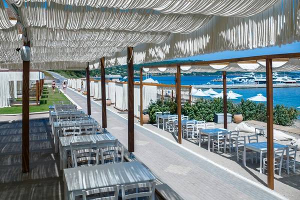 Außenbereich des Miraggio Thermal Spa Resorts mit weißen Tischen und Stühlen unter einer Pergola mit Blick auf das Meer.