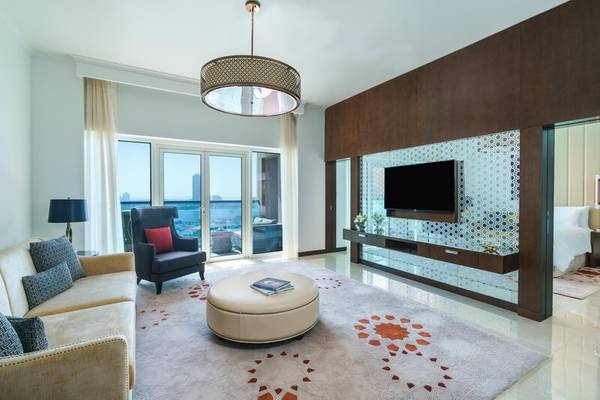 Modernes Hotelsuite-Wohnzimmer mit Sofa, Sessel, Couchtisch, Fernseher und Stadtblick
