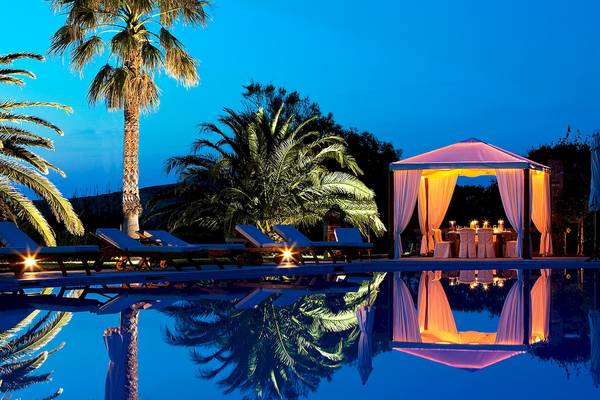 Nachtansicht des Pools mit illuminierten Sonnenschirmen und Lounge-Sesseln im Yria Island Boutique Hotel & Spa.
