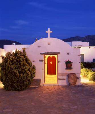 Die Kapelle des Yria Island Boutique Hotel & Spa bei Nacht mit einem roten Eingang und einem Kreuz auf dem Dach.